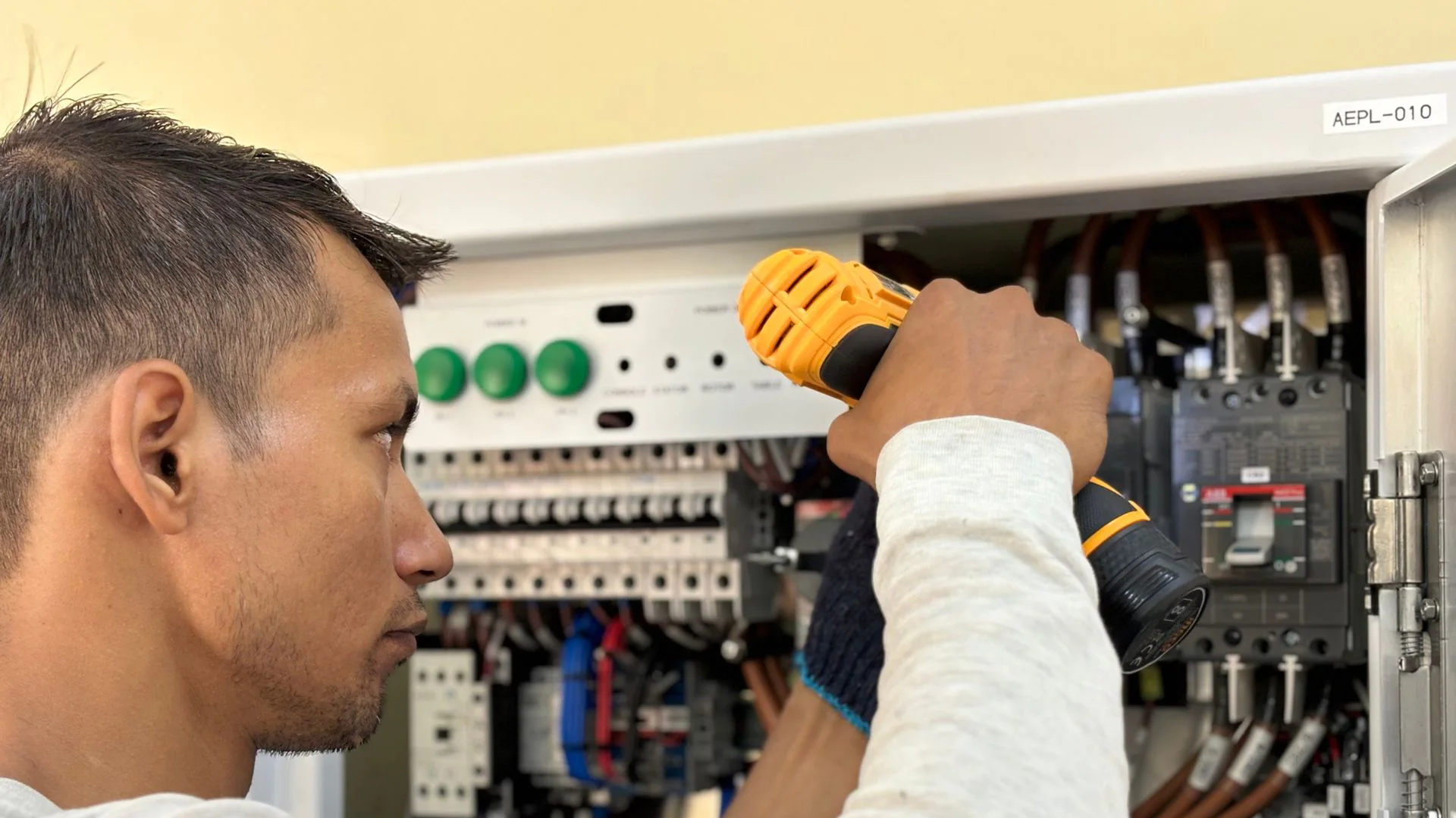 An electrician working inside an electrical panel.