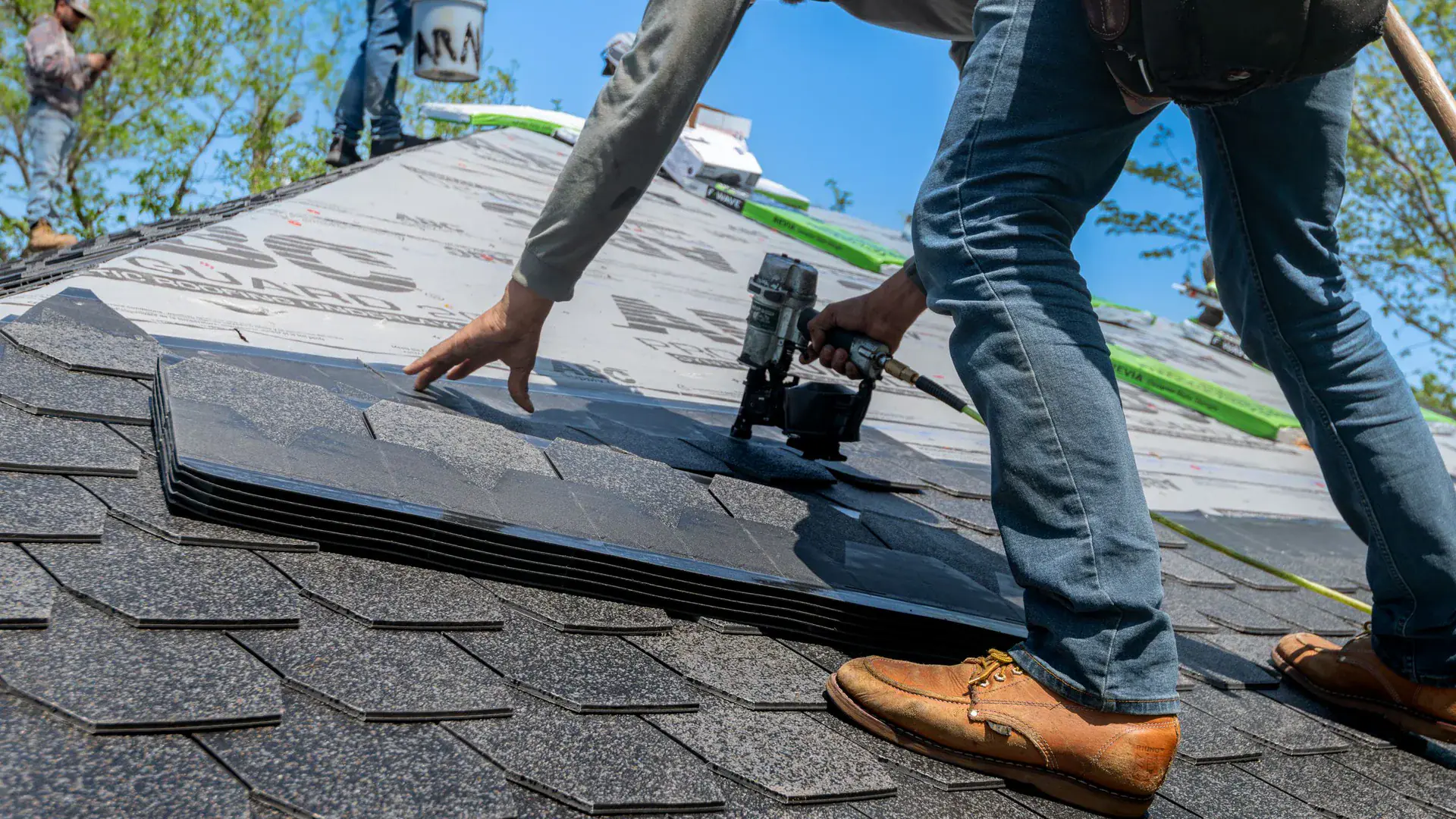 A roofer installing shingles on a residential roof.