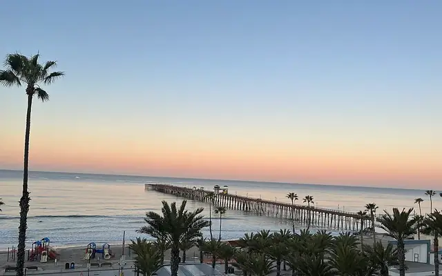 Oceanside Pier at sunrise, seen from above the beach and palm trees