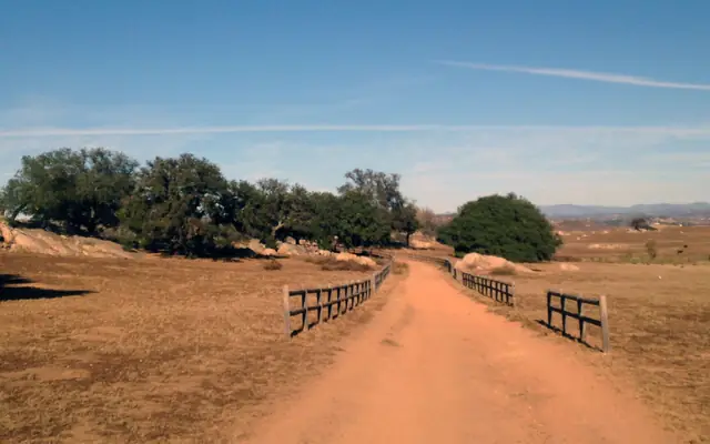 A dirt road with wooden fences crossing the Ramona Grasslands