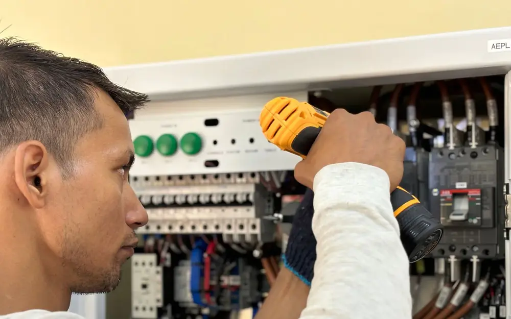 An electrician working inside an electrical panel