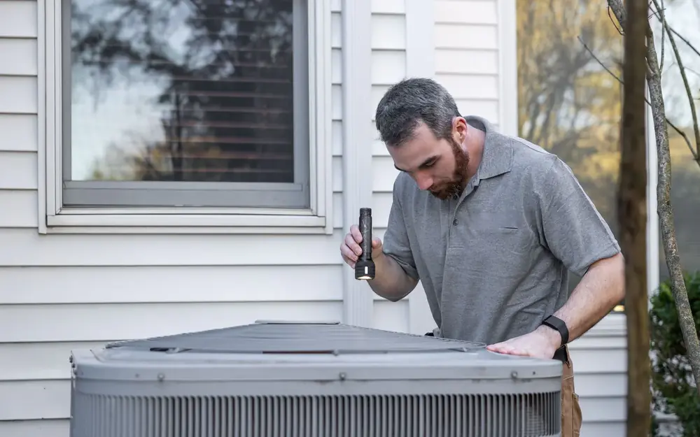 A technician inspecting an outdoor air conditioning unit