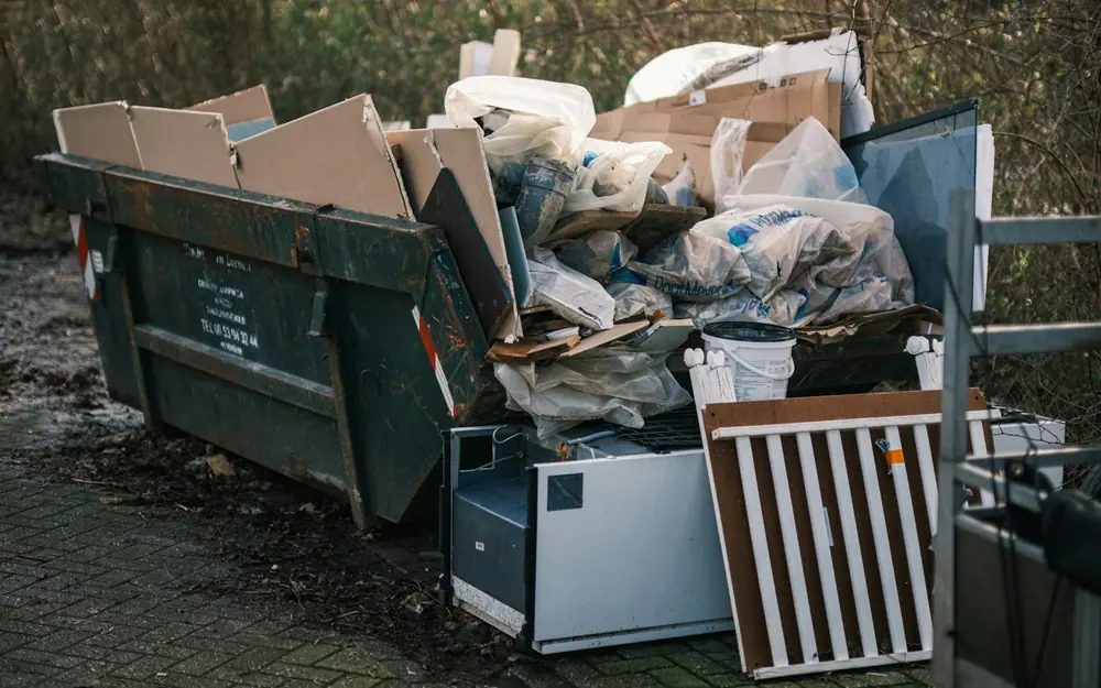 A dumpster filled with boxes, bags and old furniture