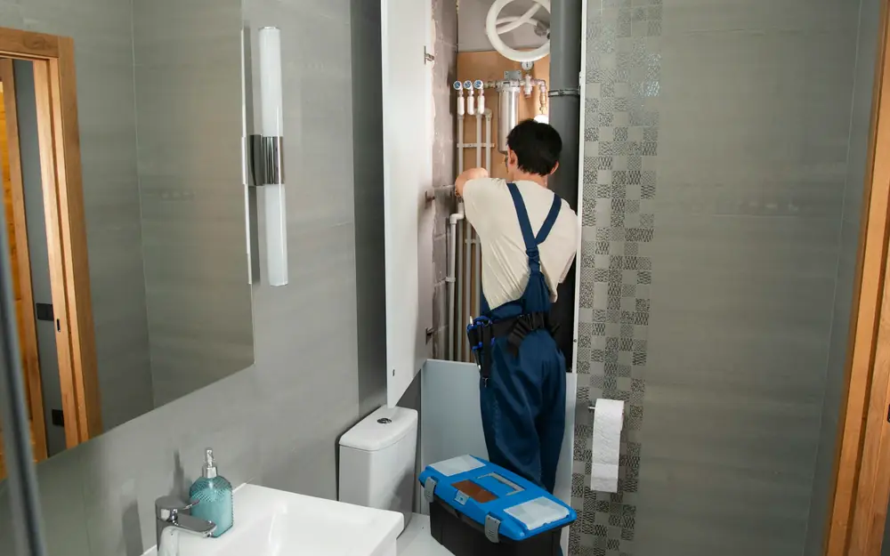 A plumber working on pipes in a bathroom