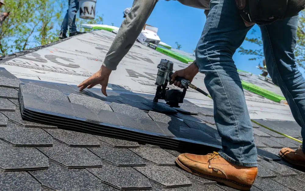 A roofer nailing shingles on a house roof